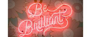 An image of a red neon sign spelling the phrase 'Be Brilliant'. 